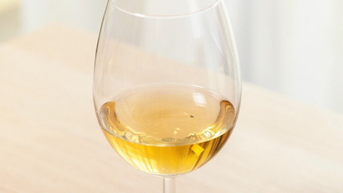 Фруктовая муха безжизненно плавает в бокале с вином, как мрачное напоминание об опасностях обжорства