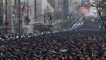 Тысячи полицейских маршируют по улицам, оплакивая полицейского, которого застрелили, когда он чесал ухо пистолетом